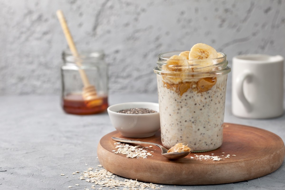 A glass of peanut butter overnight oats. In the background is a glass of honey.