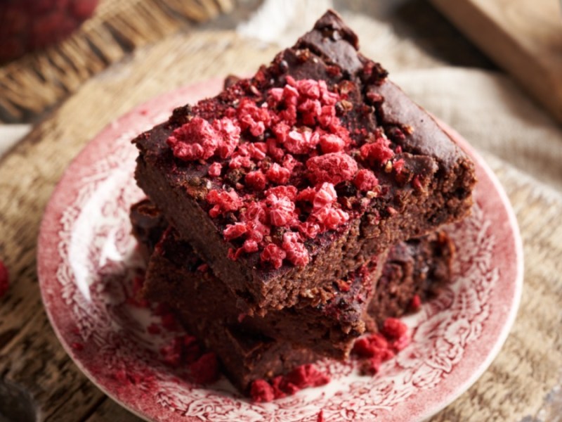 Two pieces of oatmeal chocolate cake stacked on top of each other on a plate.