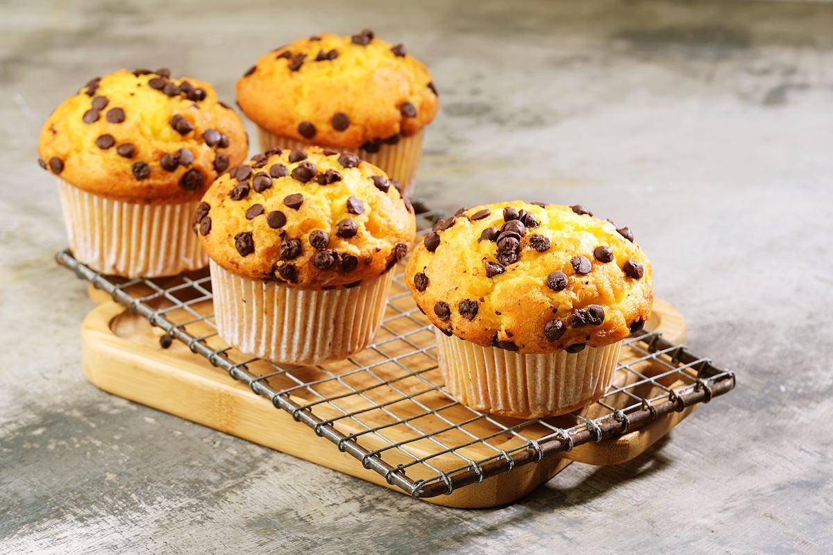 4 chocolate chip oat muffins on a wire rack placed on a wooden board.
