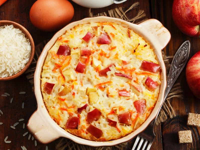 An overhead view of a rice pudding bake with apples. Around it are ingredients.