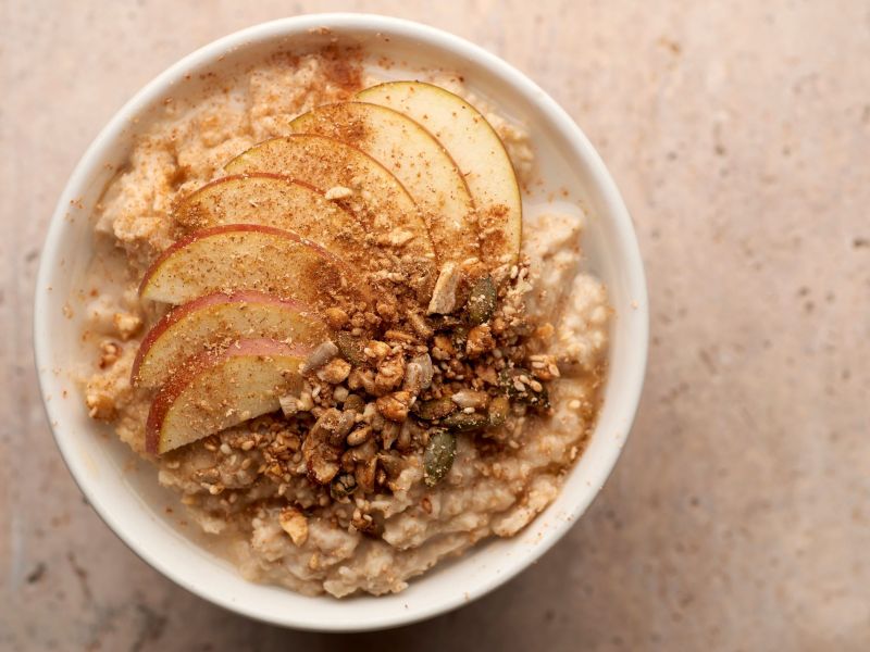 Apple strudel oatmeal, served in a white bowl, topped with apple slices, walnuts, and cinnamon