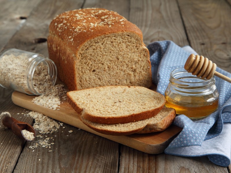 A sliced honey oat bread on a wooden board.