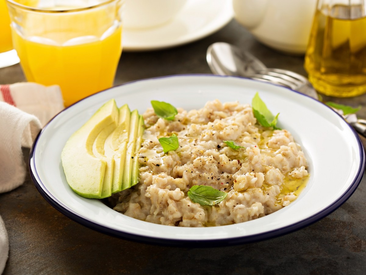 Oatmeal with avocado and olive oil on a plate, accompanied by drinks.