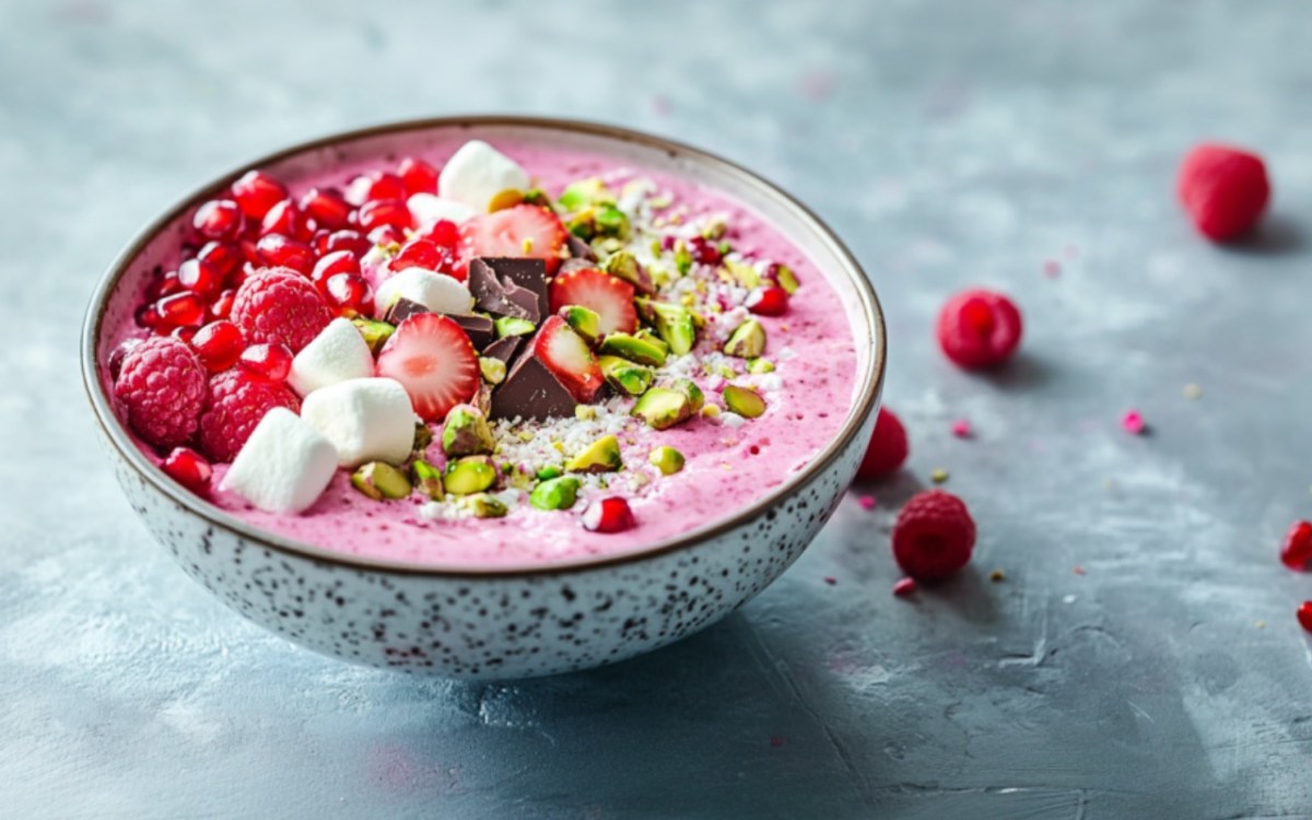 A bowl of pink oatmeal with toppings.