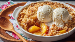 Peach crumble in an oval, white baking dish.