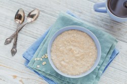 Scottish porridge in a light blue bowl, two spoons lying next to it.